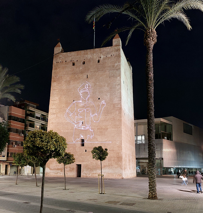 Torre iluminada con dibujo de agente de Policía Nacional en el casco histórico de Torrente. 